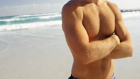 portrait of male surfer standing with arms crossed in the beach