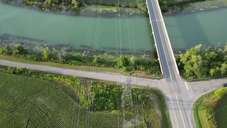 Líneas-De-Energía-Eléctrica-Por-Encima-Del-Agua-Del-Río-En-El-Campo-Rural-Antena-Inclinada-Hacia-Abajo