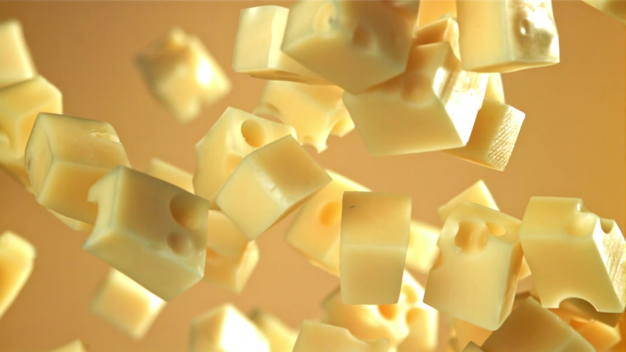 Cubetti di formaggio che cadono al rallentatore su sfondo giallo