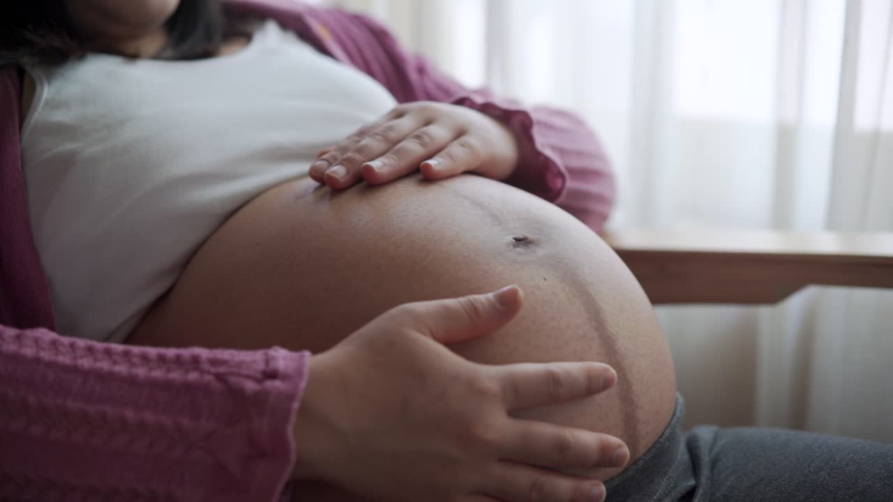 Mujer embarazada feliz y esperando un bebé en casa
