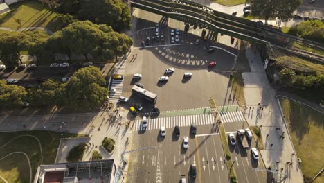 Aerial-tilt-down-over-junction-with-traffic,-cars-and-bus-crossing-road-during-golden-hour-in-Buenos-Aires