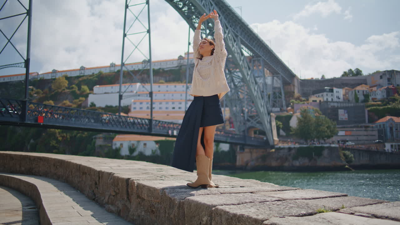 Happy tourist walking river bank cityscape back view. Joyful woman raising arms