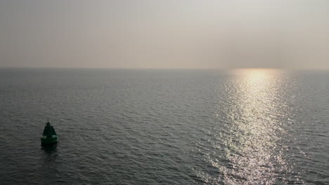 Tranquil-scene-of-a-sea-buoy-floating-at-sunset-or-sunrise-over-the-water-horizon