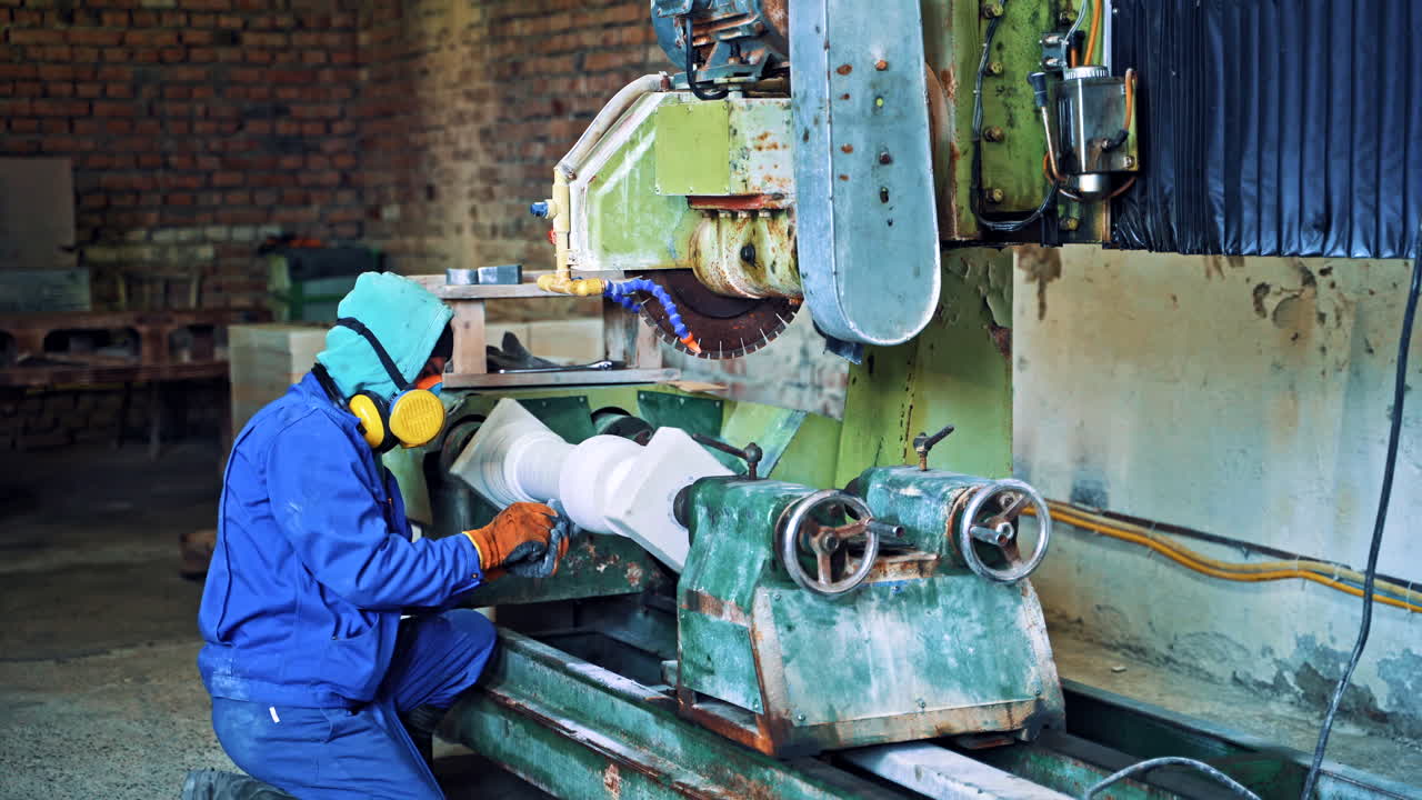 Worker man in special uniform with mask polishing stone in workshop. Laborer is working at the grinder machine on the old factory background. Camera moves forward.