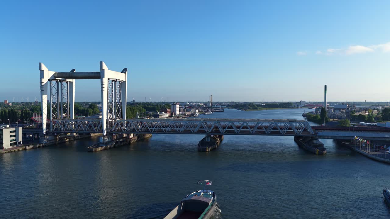 Slow drone pull-away view of the Pegasus vessel nearing the Zwijndrecht Bridge on the Oude Maas River, with Dordrecht’s industrial edge in frame