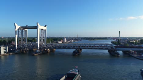 slow drone pull-away view of the pegasus vessel nearing the zwijndrecht bridge on the oude maas river, with dordrecht’s industrial edge in frame