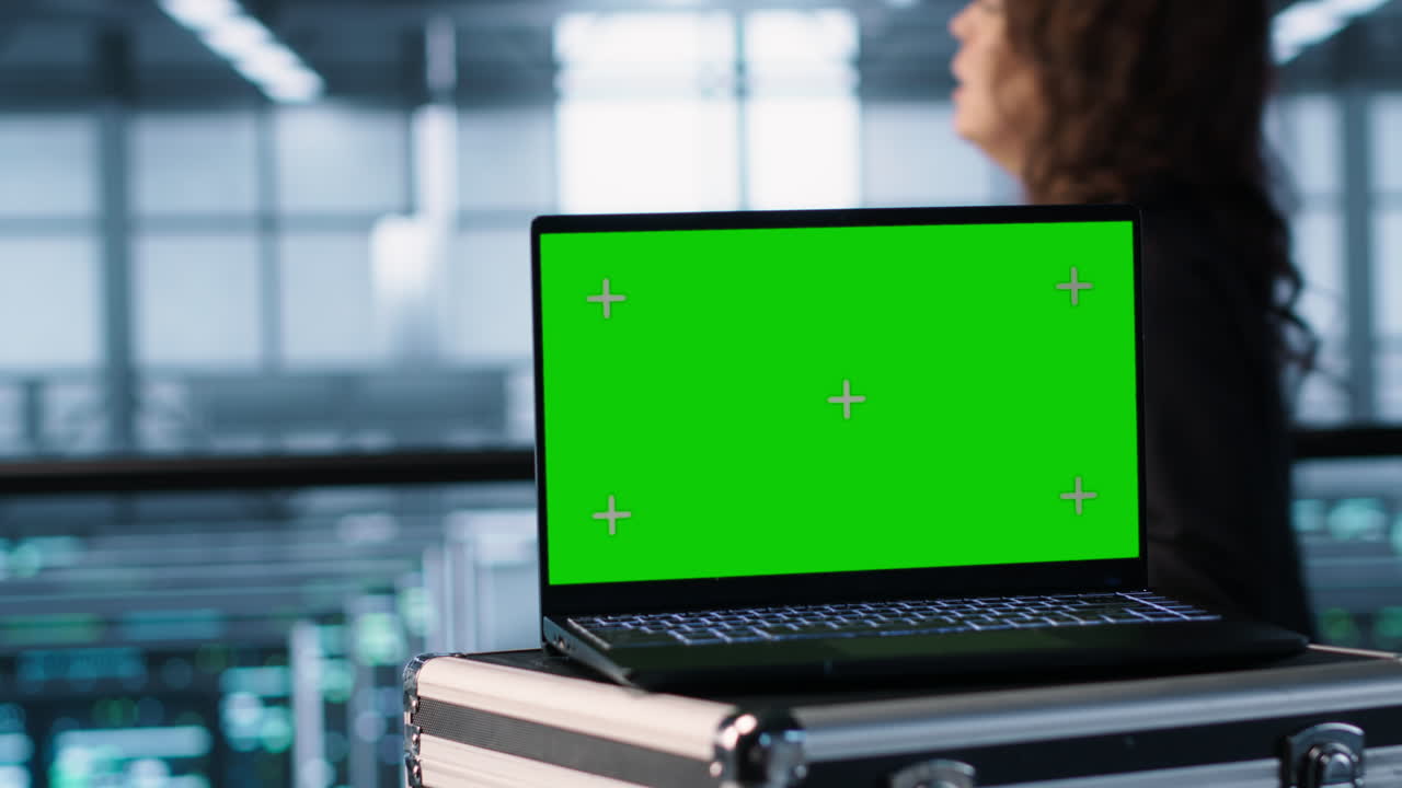 Green screen laptop in front of data center engineers inspecting servers