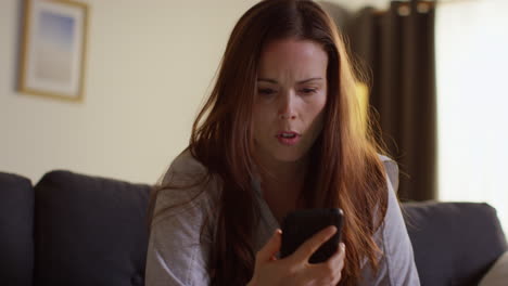 Anxious Woman Lying On Sofa At Home Looking At Mobile Phone Concerned About Social Media Or Bad News 1