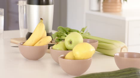 fresh fruits and vegetables on kitchen counter with blender for healthy smoothie