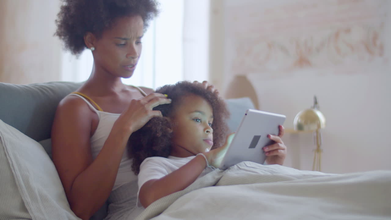 African American mother and daughter lying in bed and relaxing