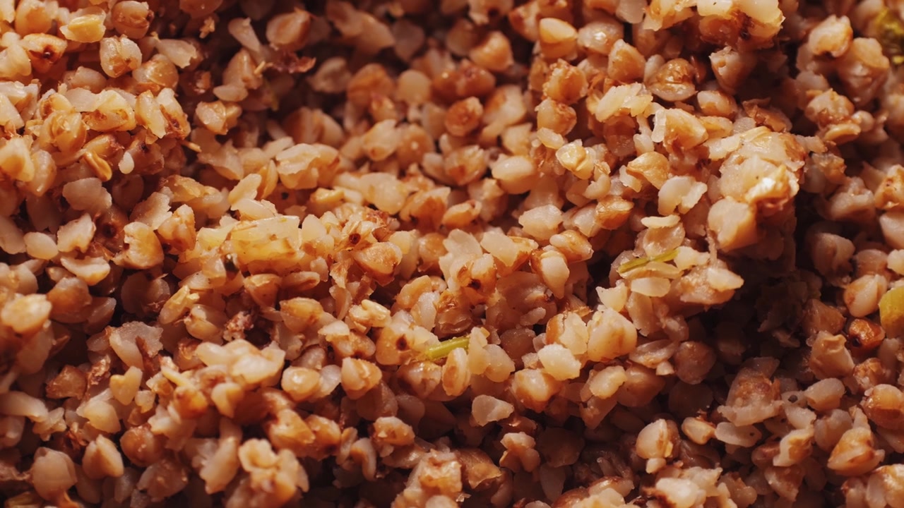 Cooked buckwheat macro, buckwheat groats close-up in a wooden spoon pouring background food video for cooking