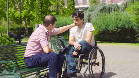 mature man cheers up disabled teenager in wheelchair.