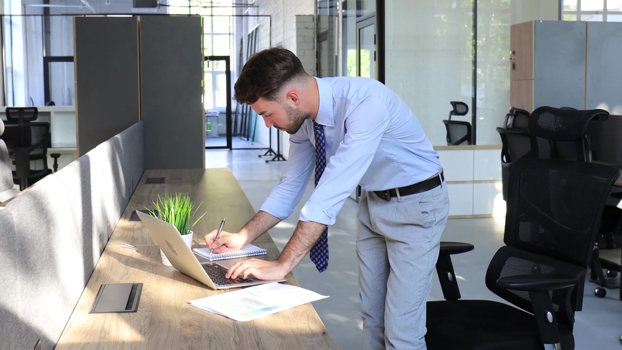 Joven empresario trabajando en su portátil y relajándose en una oficina moderna