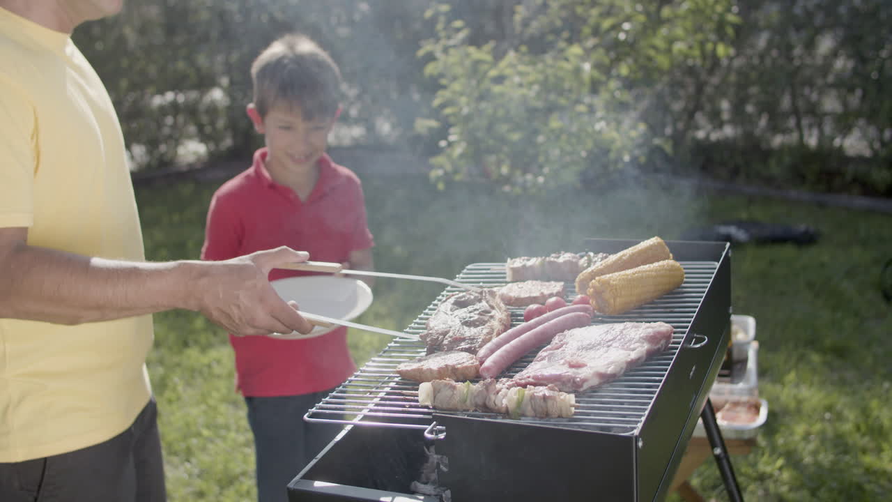 hombre poniendo costillas de cerdo a la parrilla con pinzas en el plato de su hijo