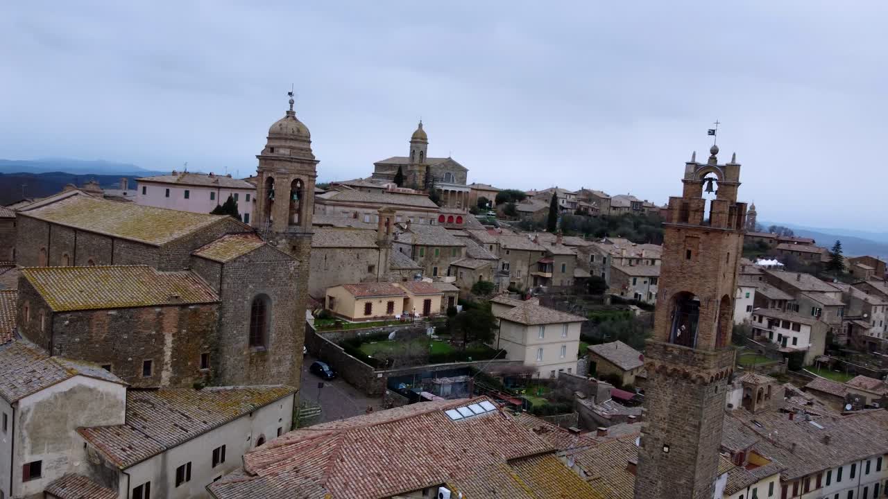 orbitando alrededor de la torre del reloj en el hermoso pueblo de montalcino, italia, aerial