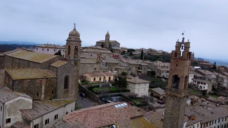 Orbiting-around-clock-tower-in-beautiful-hilltop-village-Montalcino,-Italy-,aerial