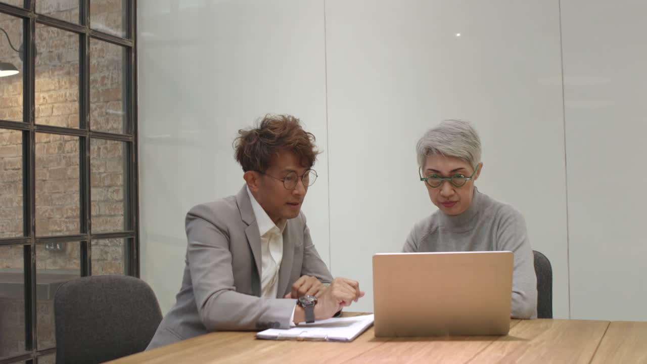 Consulente aziendale maschio asiatico consiglia imprenditrici di mezza età sull'accesso alle informazioni di marketing