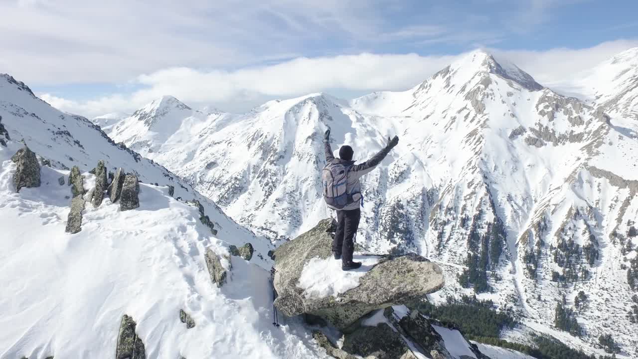 escalador celebrando la cumbre en montañas nevadas