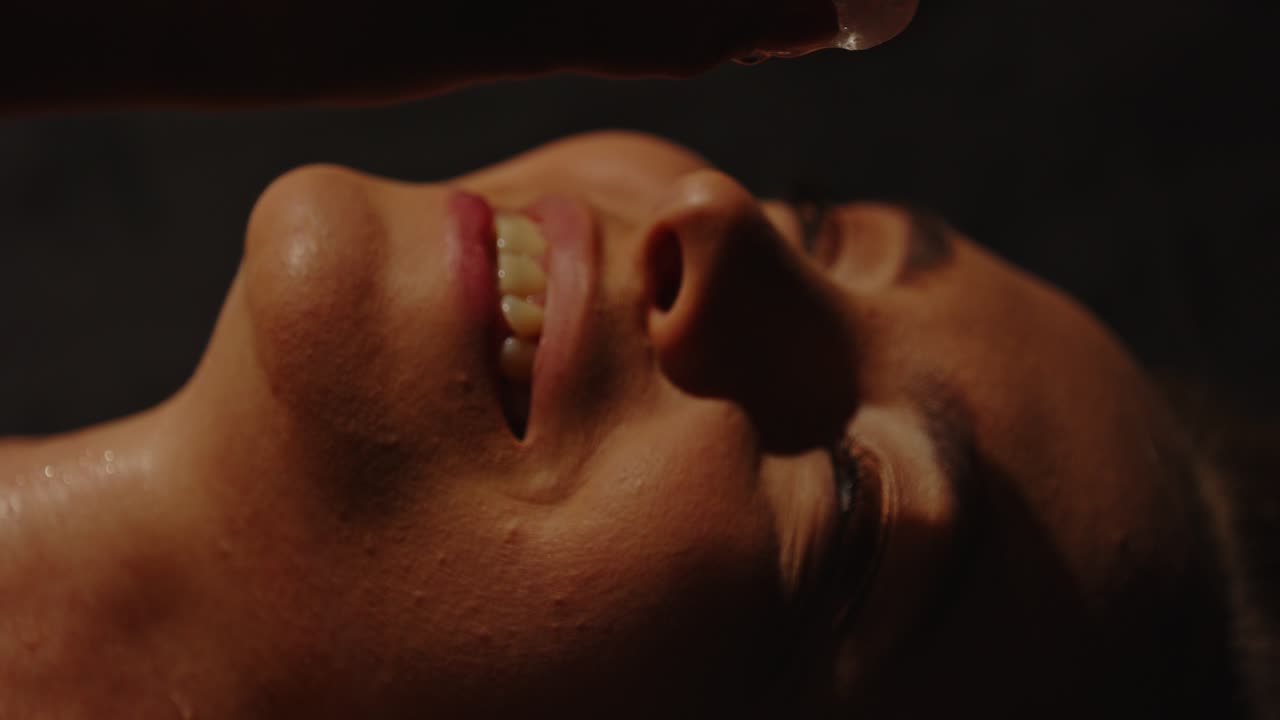 A beautiful woman sensually putting an ice cube to her mouth