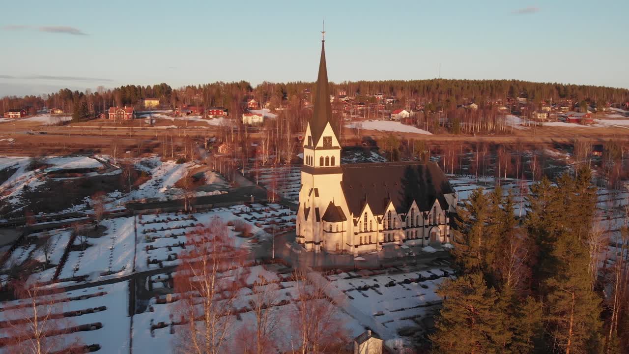 Aerial front view of majestic Scandinavian church-cemetery in Vindeln, Sweden. Shoot on a cold snowy morning.