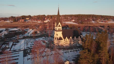 aerial front view of majestic scandinavian church-cemetery in vindeln, sweden. shoot on a cold snowy morning.