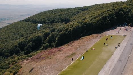 drone shot of a paraglider taking of from a start at the side of a mountain