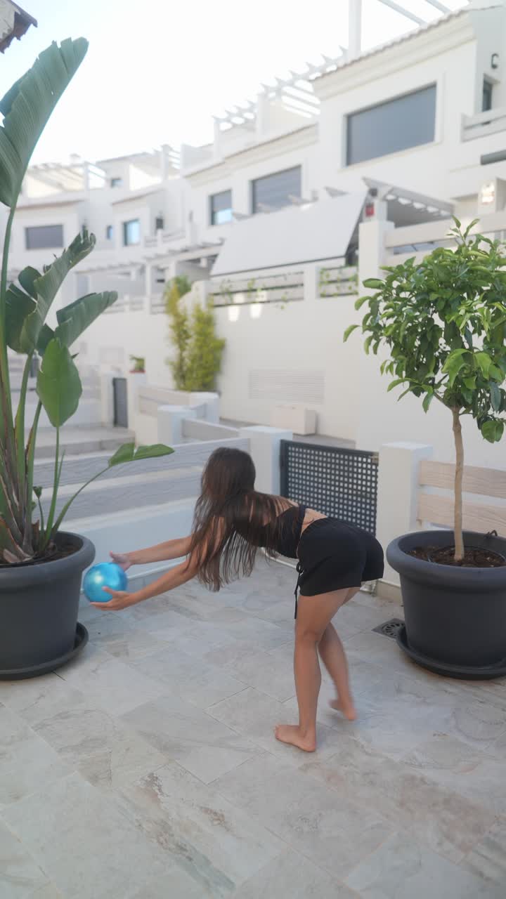 niña jugando con una pelota azul en un patio