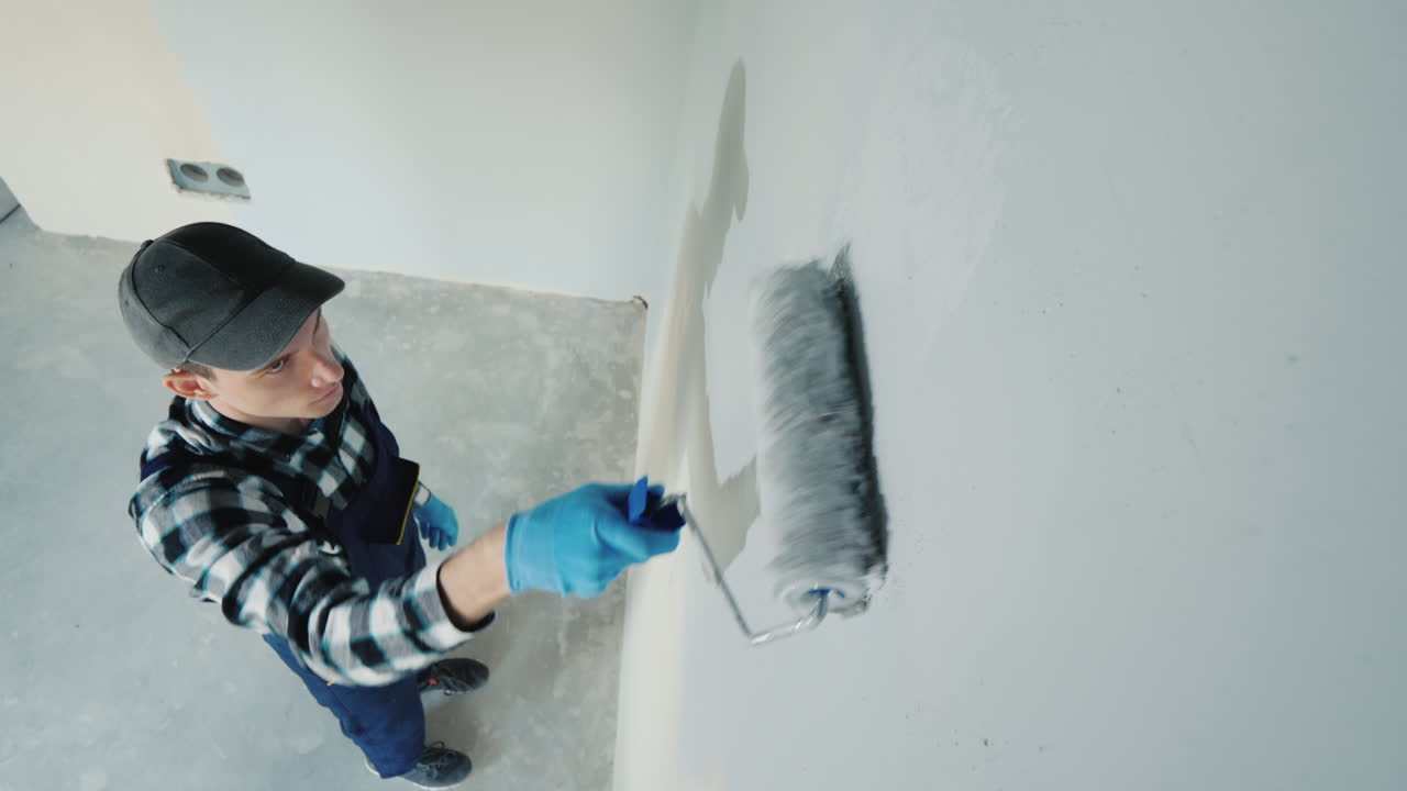 vista superior del constructor masculino pinta la pared con rodillo