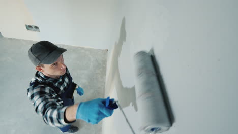 top view of male builder paints wall with roller