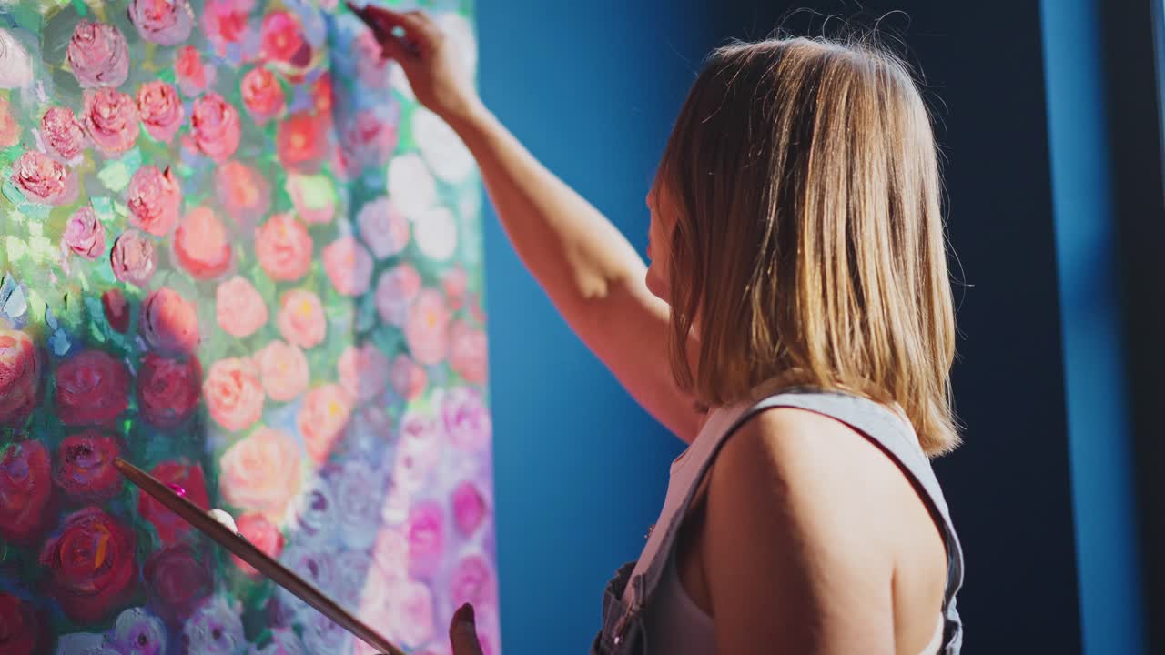 Kvindelig kunstner maler blomsterkunst med paletkniv i atelier