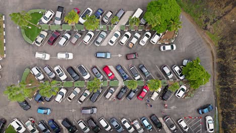 drone top down trucking pan above cars circling in parking lot of supermarket