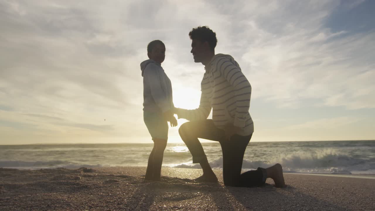padre hispano abrazando a su hijo en la playa al atardecer