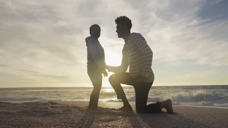 padre hispano abrazando a su hijo en la playa al atardecer