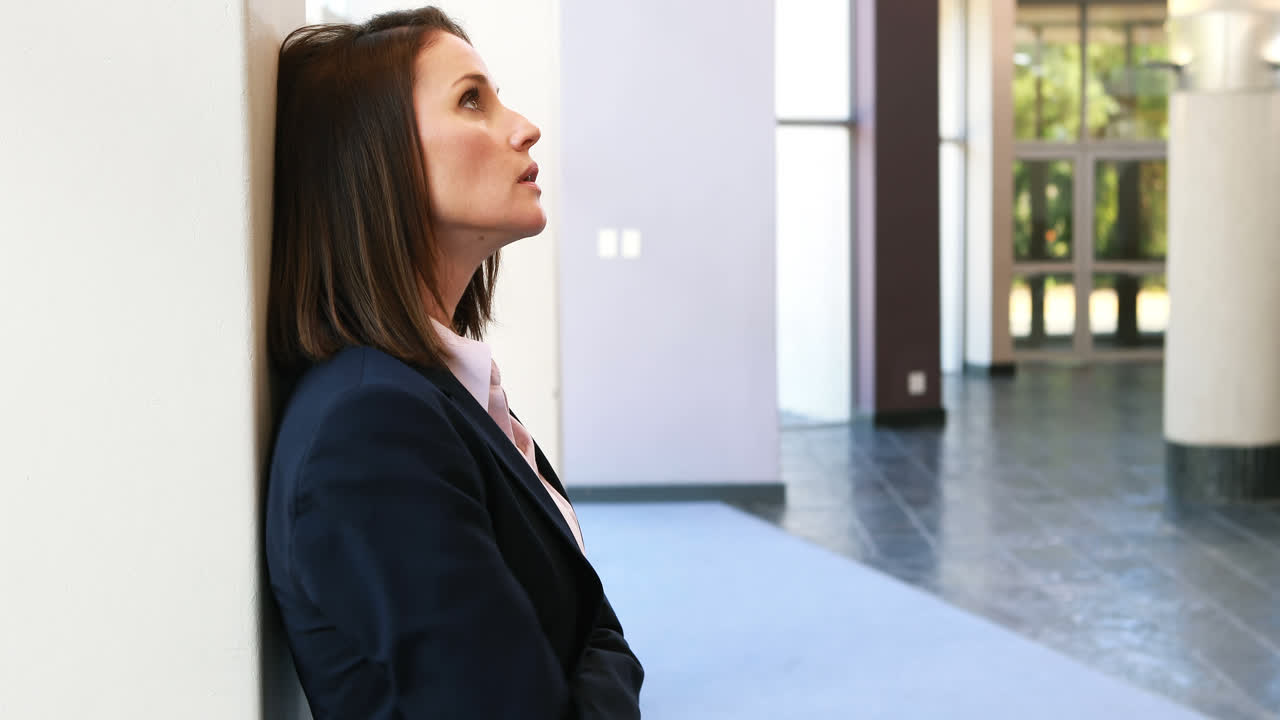 Donna d'affari turbata appoggiata al muro 4k