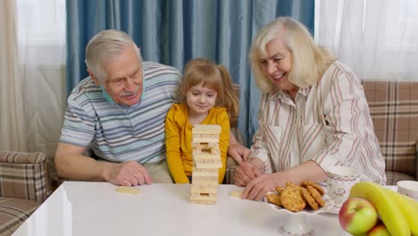 coppia anziana nonni e nipote godendo gioco da tavolo costruzione torre da blocchi a casa