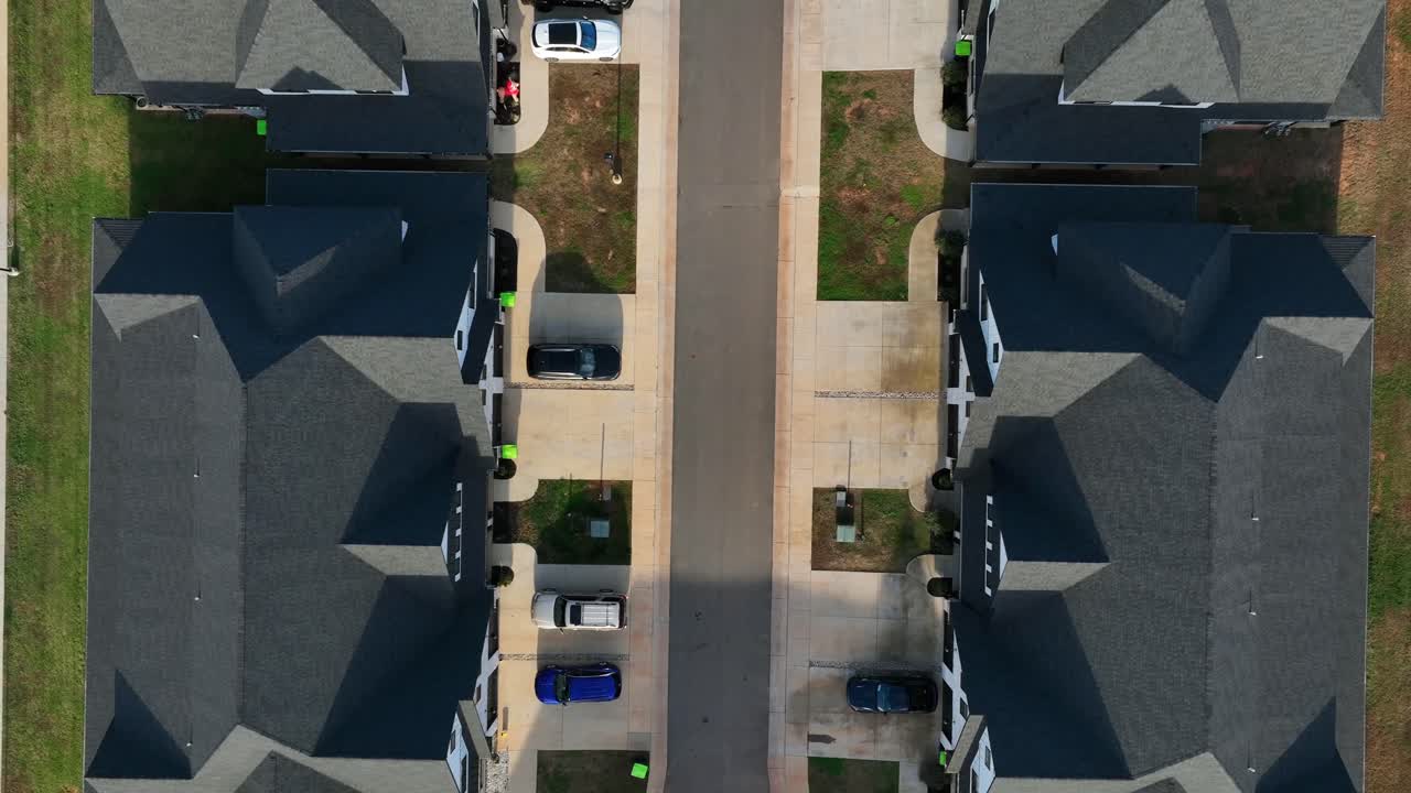 Luksusvillaer og -palæer med gråt tag i nybygget boligområde i en amerikansk by. Biler kører på vejen på en solskinsdag i USA. Top-down luftoptagelse i stigende vinkel
