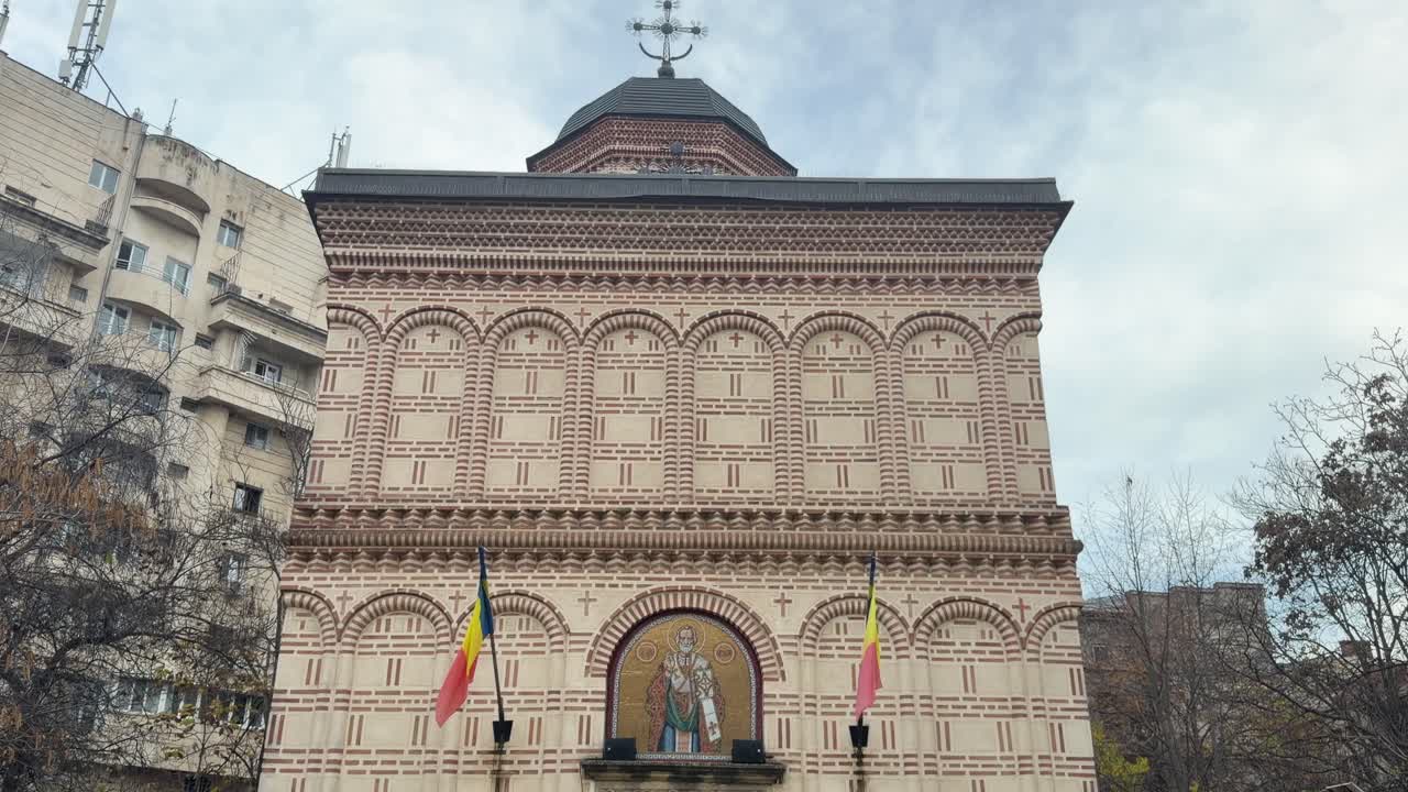 front view of Mihai Vodă Monastery Bucharest showing ornate brick facade and flags