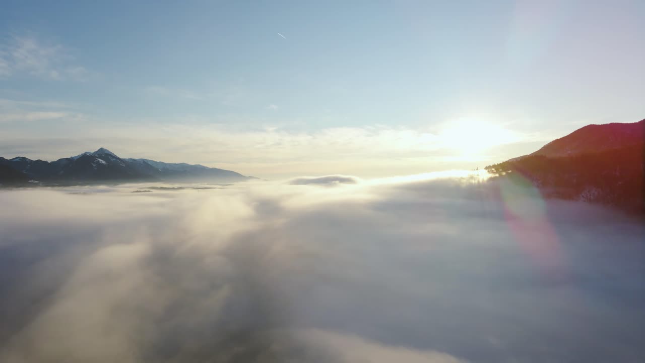 Drone shot  of an incredible landscape covered under the fog with surrounding mountains in the morning at winter time in Slovenia captured in 4k, drone going down under the fog