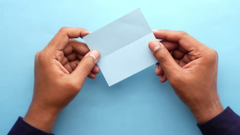 manos sosteniendo un papel azul claro en blanco