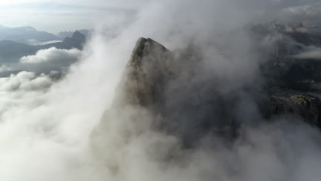 vista aérea que se inclina sobre la niebla, revelando un pico rocoso de piedra caliza en el tirol, italia