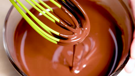 green whisk stirring smooth, melted chocolate in bowl