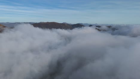 dense cloud inversion covering mountainous landscape below blue sky