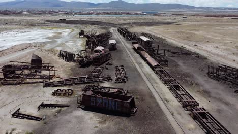 flyover of abandoned train cars on altiplano track near uyuni, bolivia