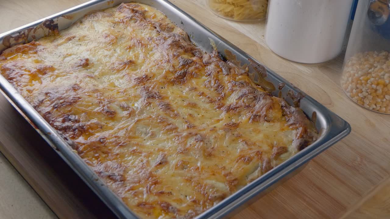 Getting a Freshly Cooked Hot Lasagne Out of the Oven and Placing it on the Kitchen Counter to Cool