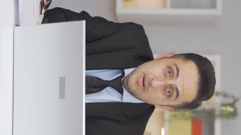 Vertical-video-of-Home-office-worker-man-looking-at-camera-curious-and-confused.