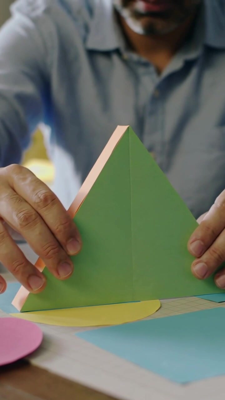 Video verticale: Uomo in camicia blu che allinea un triangolo su dischi colorati a un tavolo per un modello