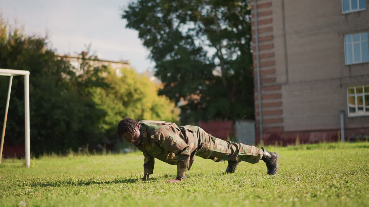 Fitness Drill Outdoors, Military Personnel Engaged In Core Training Within Urban Park Setting, Individual In Camouflage Outfit Practices Mountain Climbers And Planks Amid City School Playground