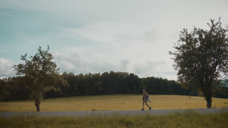 female explorer walking on road by grass in forest