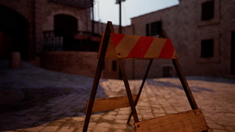 un letrero de construcción de rayas rojas y blancas en una calle de adoquines en una ciudad histórica.