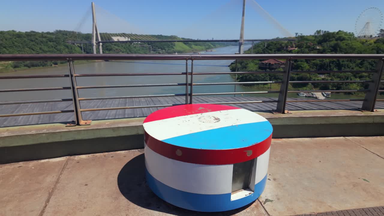 Monument med Paraguays flagfarver ved Hito Tres Fronteras-udkigspunktet i Argentina med udsigt over Paraná-floden og Integrationsbroen